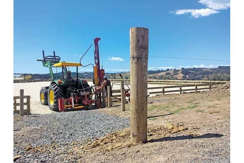 New yards constructed for horses wooden posts side mounted post rammer on John Deere